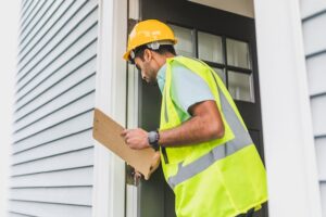 property inspector with clipboard checking structural integrity of wall