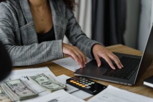 accountant counting cash and checking something on their laptop