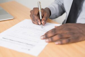 person holding a silver pen to sign a contract